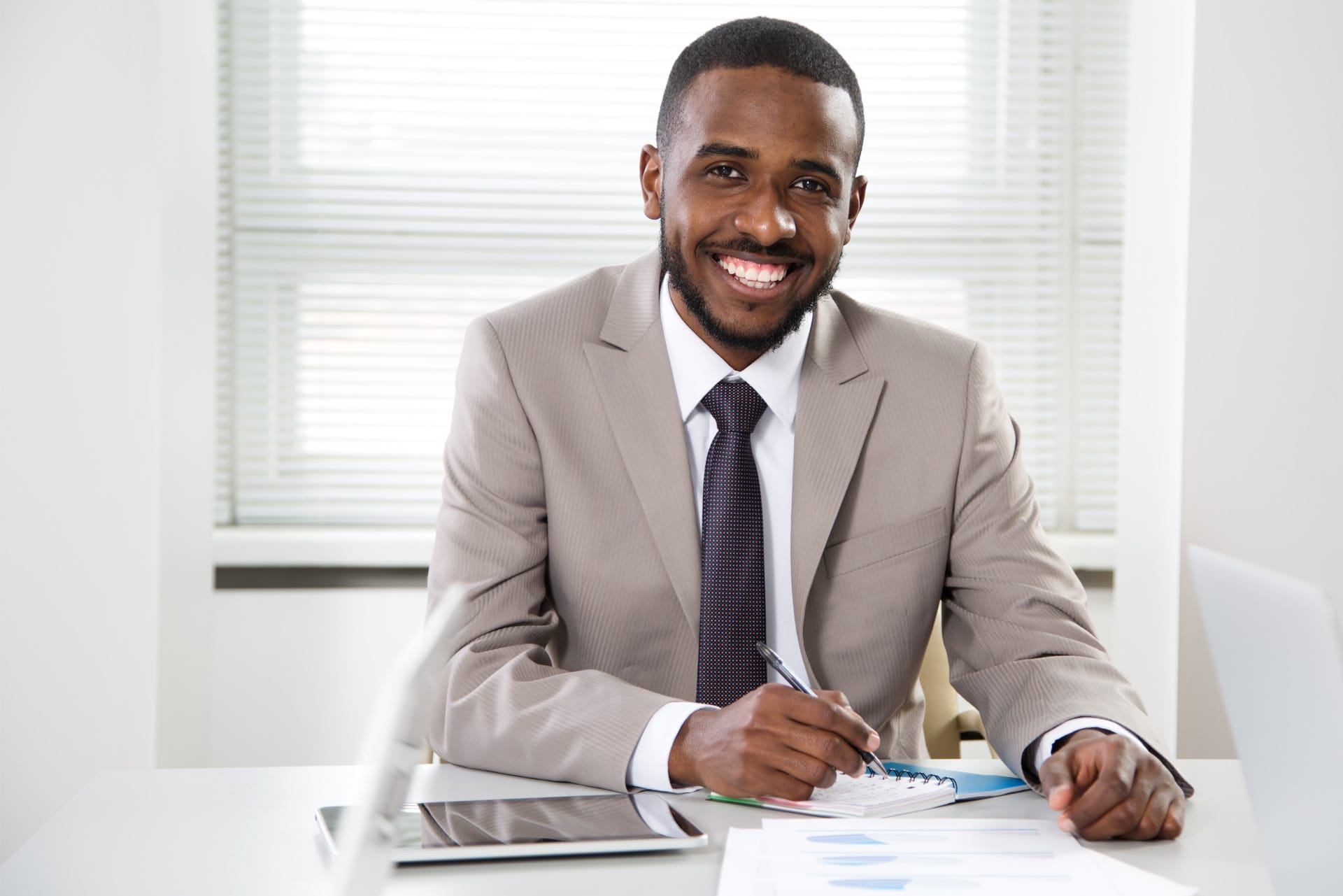 Professionnel assis derrière son bureau, souriant et fixant la caméra du regard, heureux parce qu'il utilise des chèques de direction